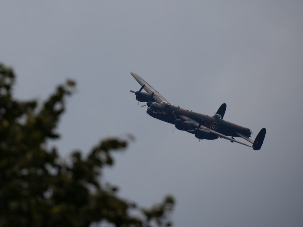 a plane flying in the air with trees in the background