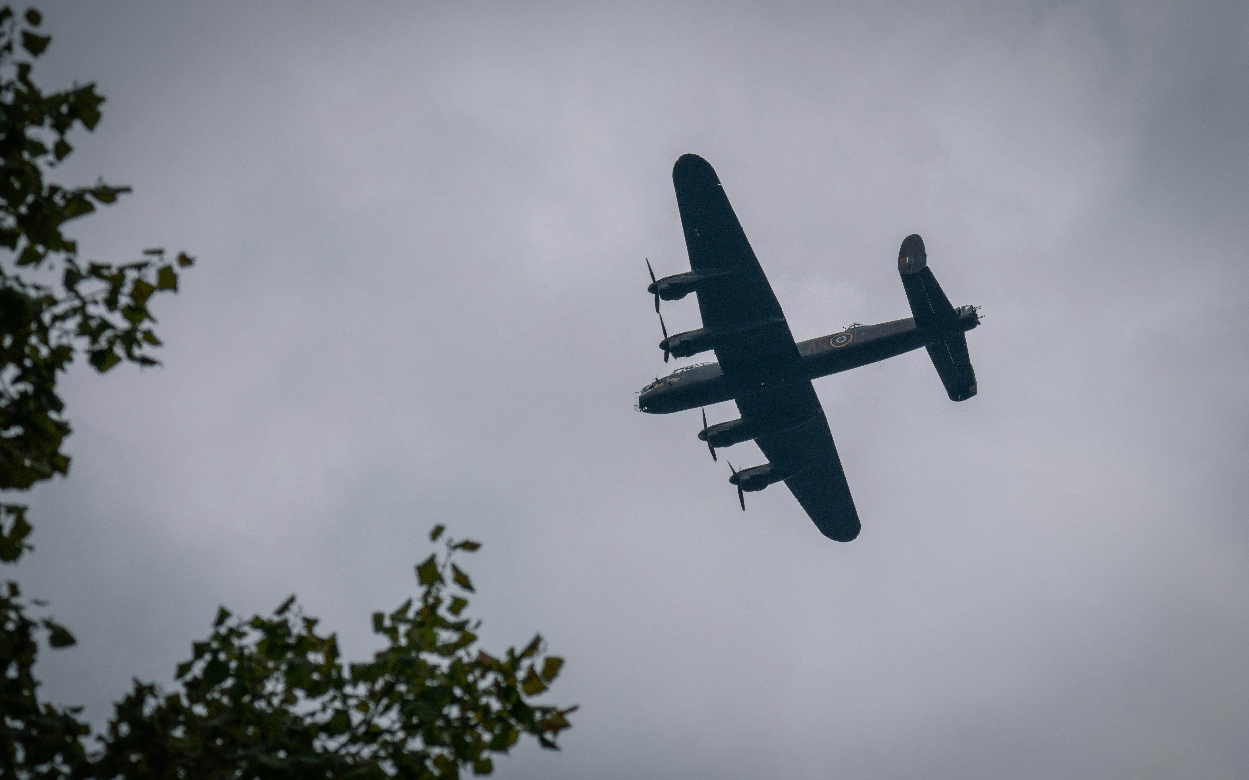 a plane flying in the sky with trees in the foreground, Avro Lancaster PA474 on a Battle of Britain memorial flight over Nottingham - 17th of September 2023.