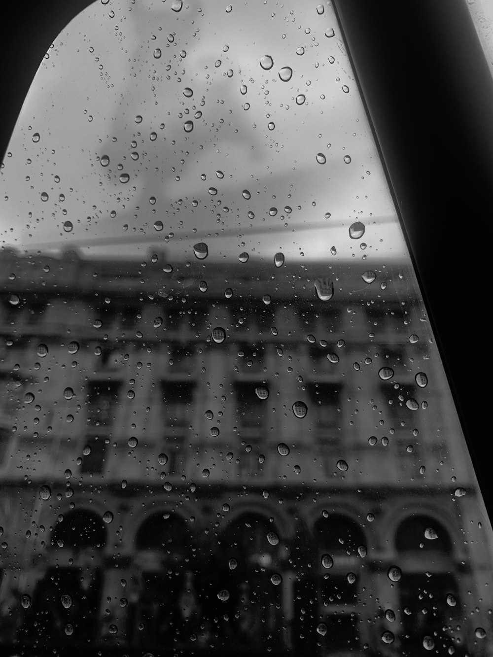 Une photo en noir et blanc de gouttes de pluie sur une fenêtre