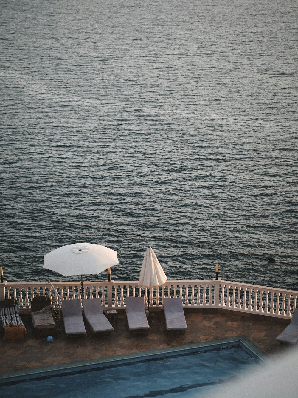 a deck with chairs and an umbrella overlooking a body of water