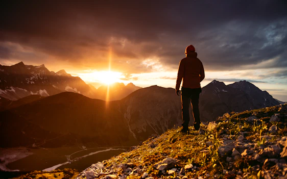 A vibrant photo of a happy traveler standing on a scenic mountain overlook during sunrise.