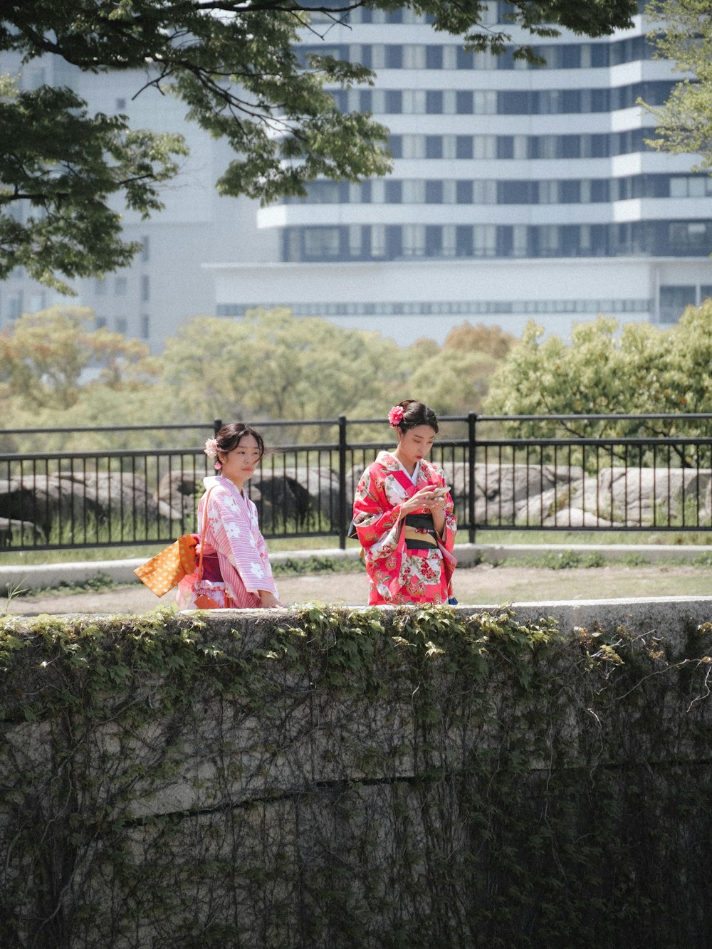 two women in kimonos walking in a park