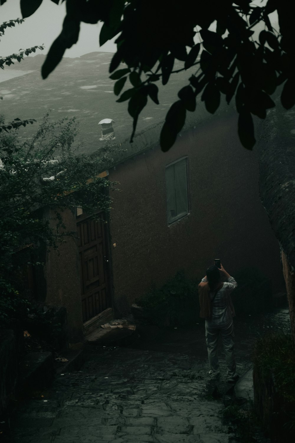 a person standing on a cobblestone road in the rain