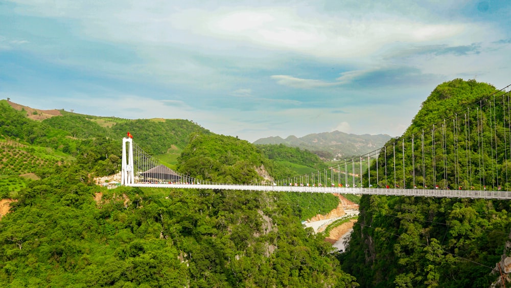 a suspension bridge over a river surrounded by lush green hills