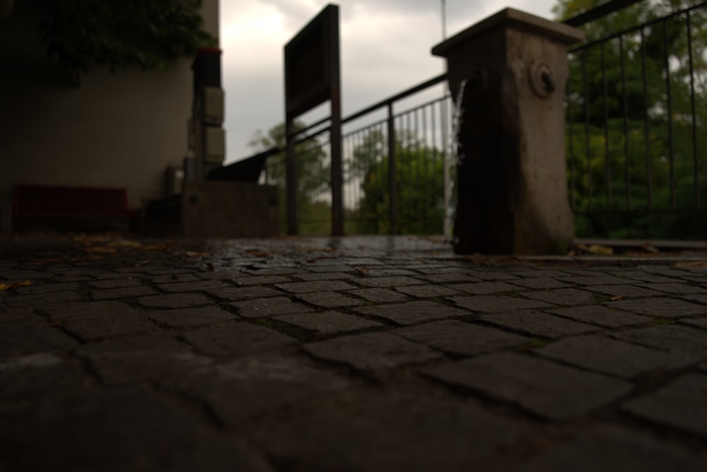 a close up of a brick sidewalk with a gate in the background