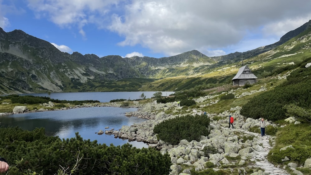 a group of people walking up a hill next to a lake