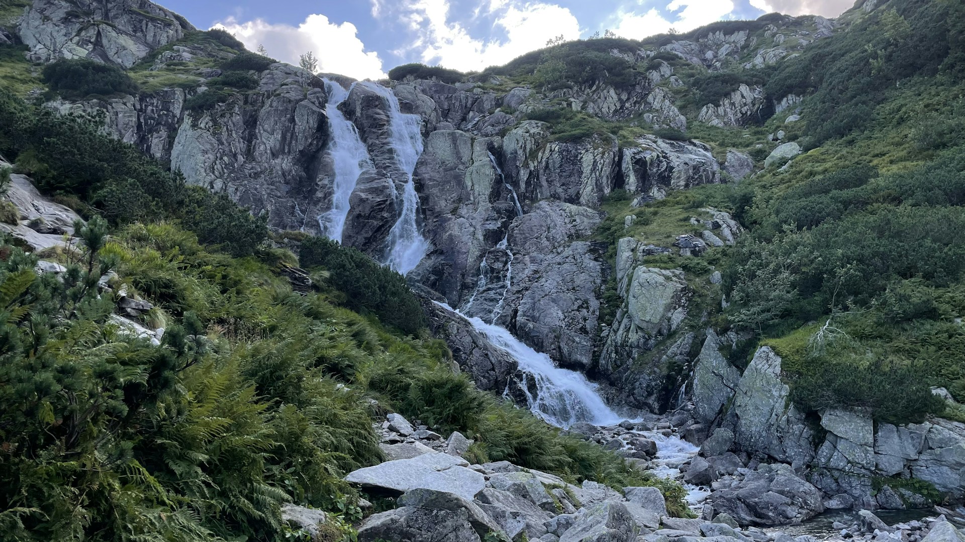 a waterfall in the middle of a lush green valley