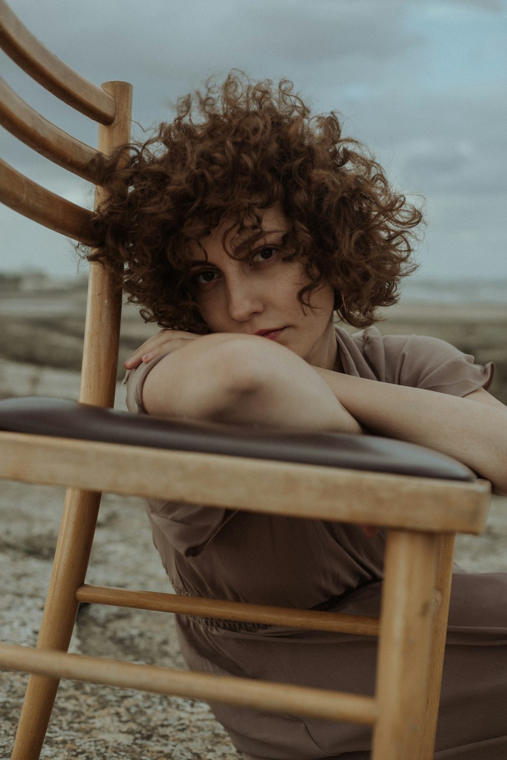 a woman sitting on a wooden chair with her arms crossed