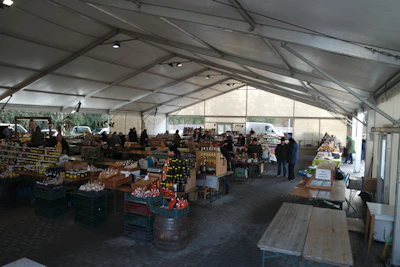 A bustling rural promotional stall with farmers engaging and examining products under a bright canopy.