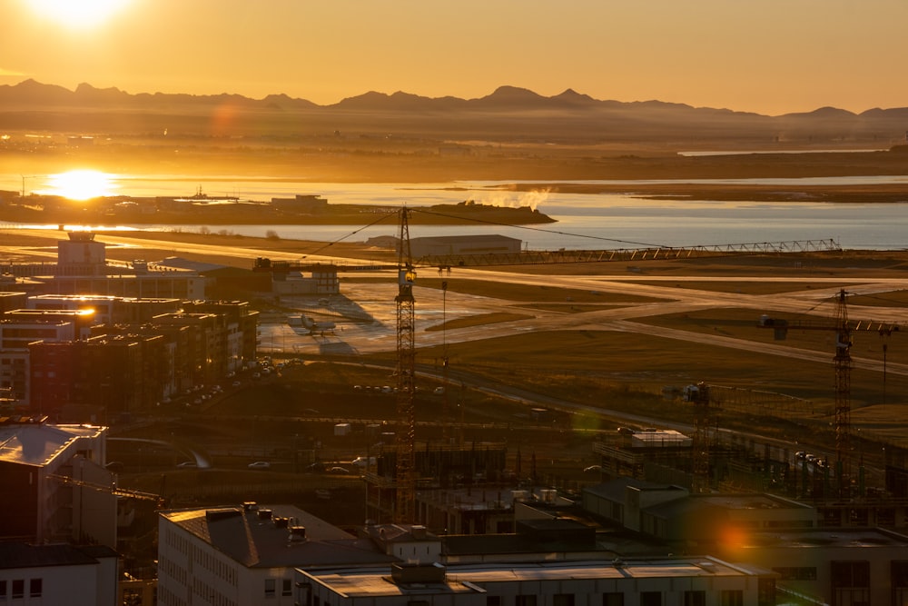 the sun is setting over a city with a body of water