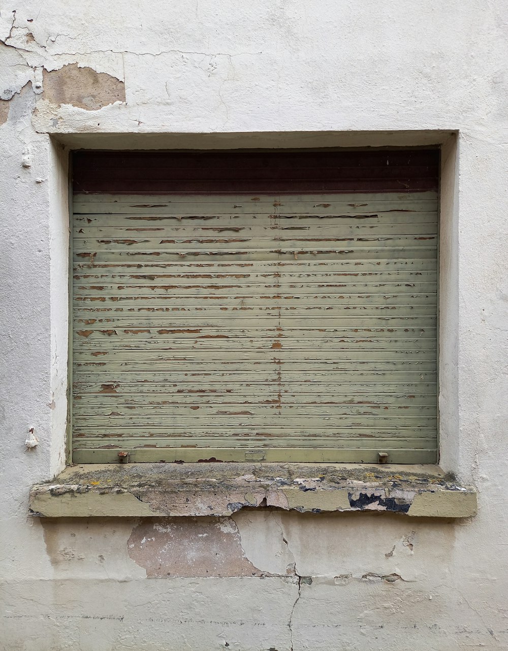 an old window with peeling paint on the side of a building