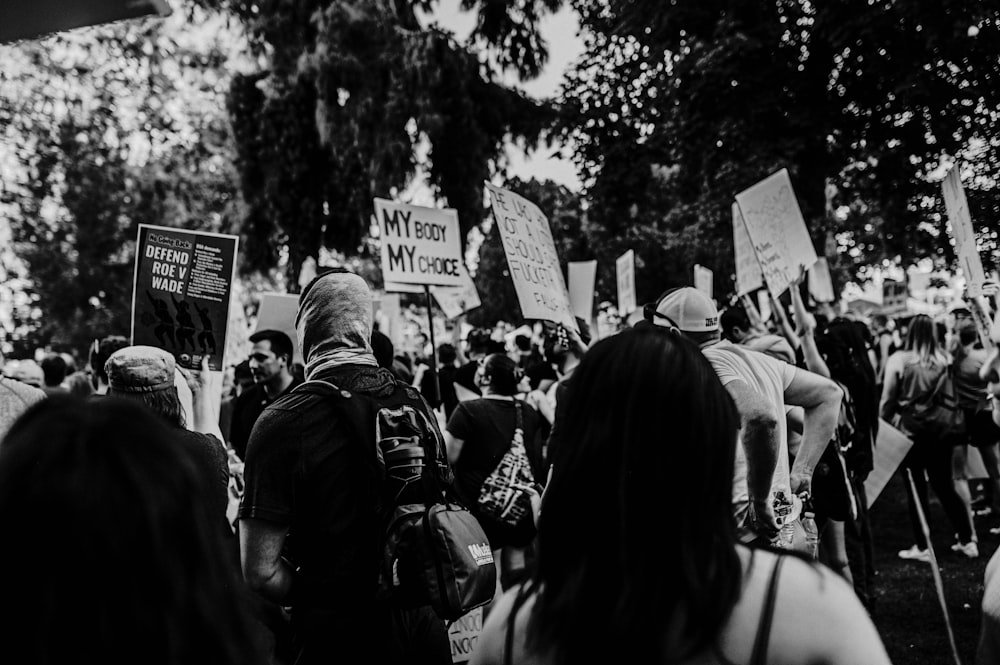 a large group of people holding signs in a park