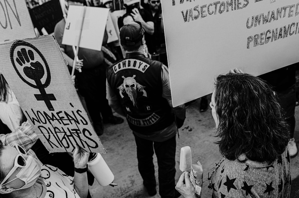 a group of people holding signs and wearing masks