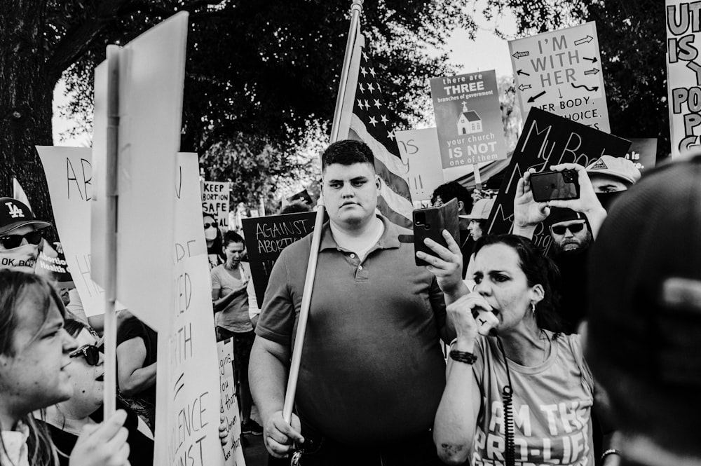 a group of people holding up signs and a cell phone