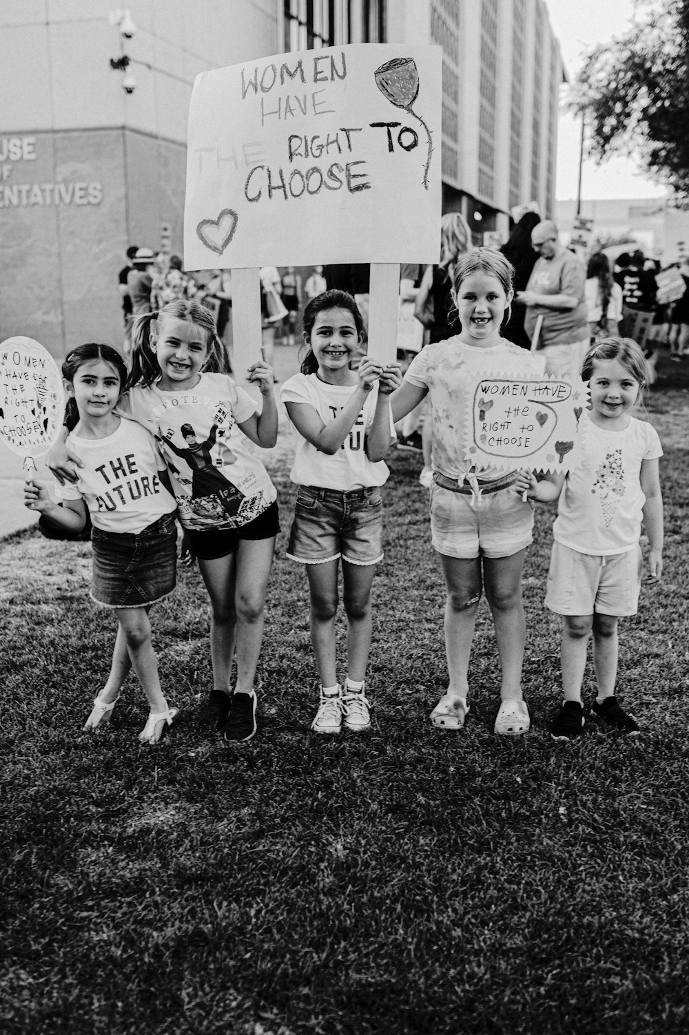 Un grupo de niños sosteniendo carteles frente a un edificio