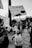 A black and white image captures a protest scene where a child in a tank top energetically holds up a sign reading 'Girls should have control of their own bodies'. Several people in the background are also holding signs and participating in the demonstration.