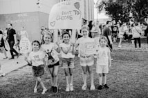 A group of young girls is standing on a grassy area holding protest signs advocating for women's rights. The text on the signs includes messages about women's right to choose. The girls are smiling and appear to be part of a larger gathering, as other people are visible in the background near a building labeled 'House of Representatives'. The image is in black and white.