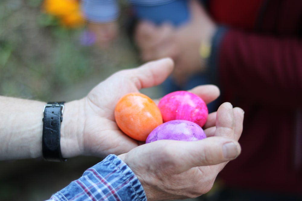 a person holding three balls in their hands