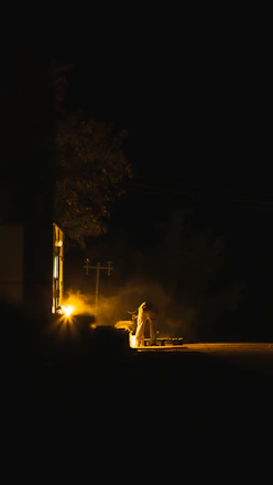 Technician repairing a commercial parking lot light fixture at dusk.