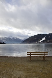 a wooden bench sitting on the shore of a lake