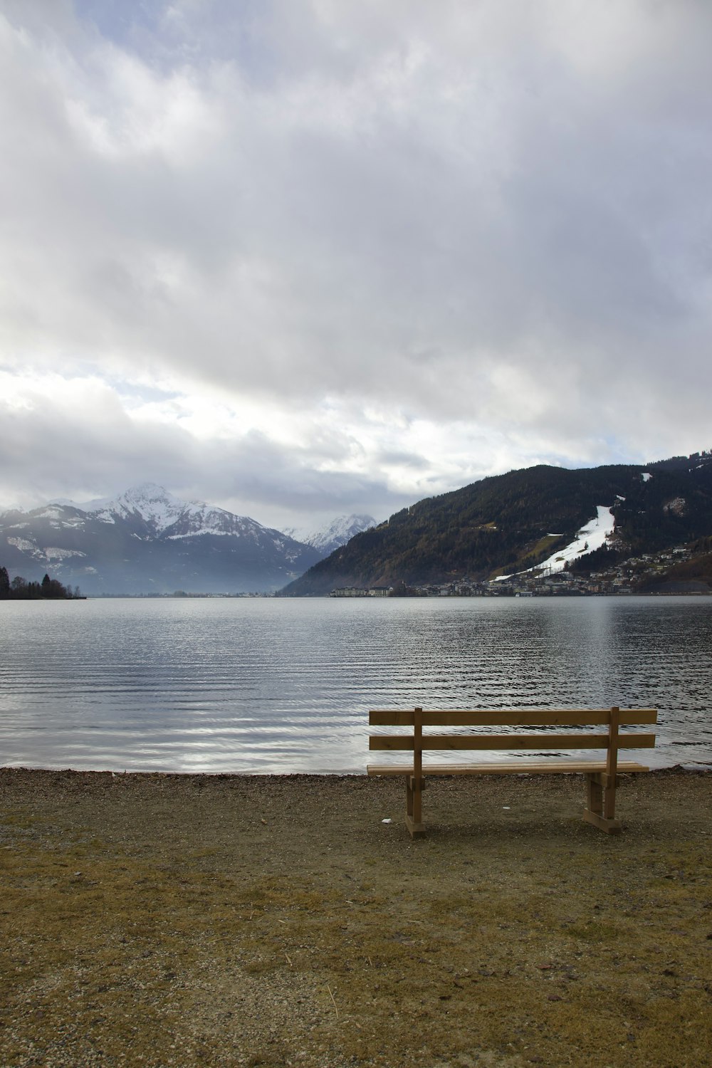 湖のほとりに座っている木製のベンチ