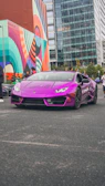 A luxury convertible parked by a famous Montreal mural, blending art and prestige.