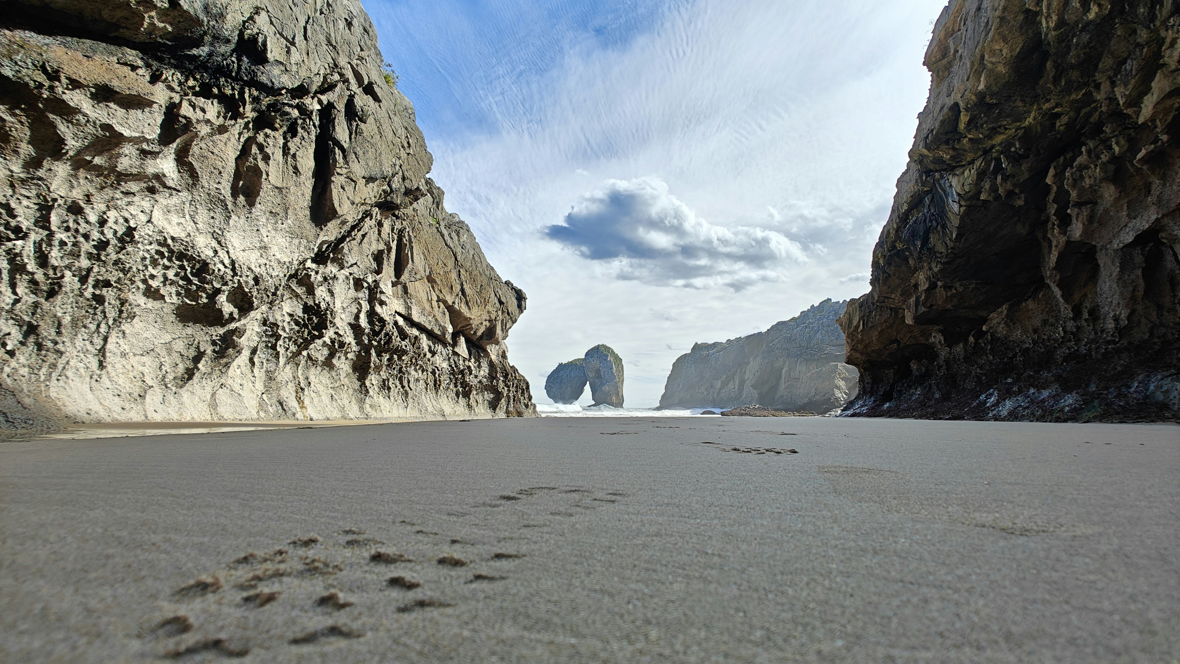 a view of a beach with a rock formation in the background, Coast near naves de llanes I. Asturias