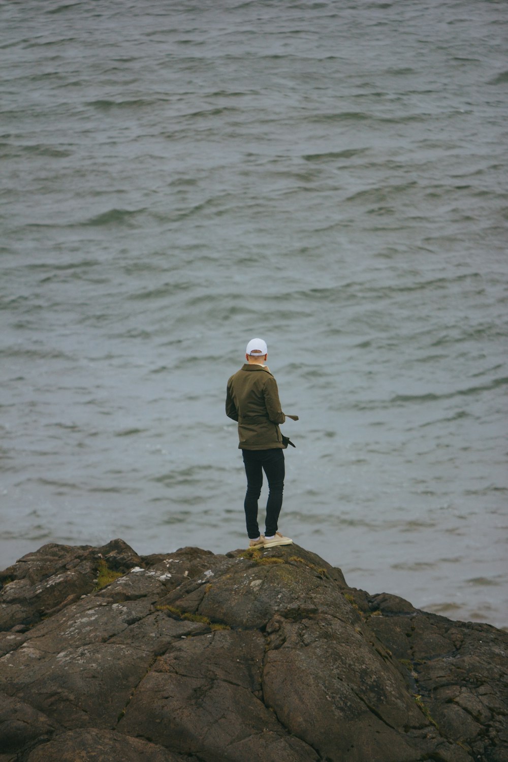 a man standing on top of a rock next to the ocean