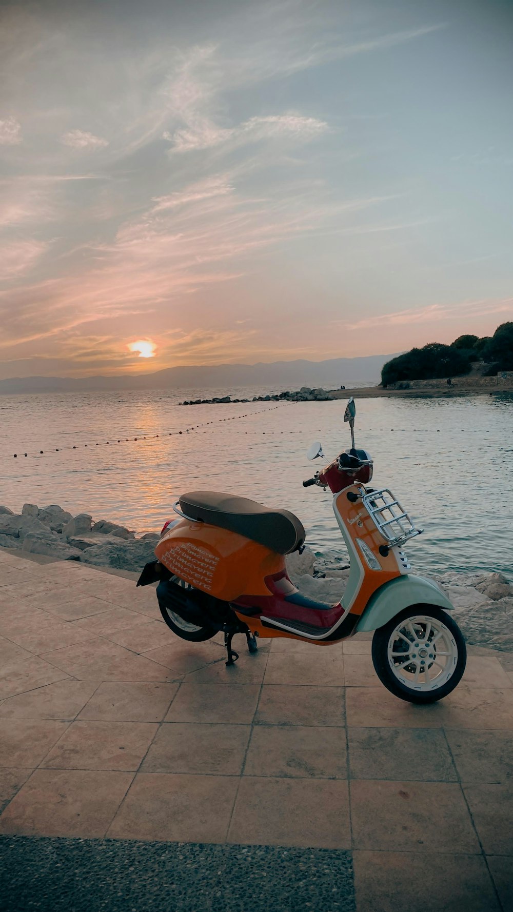 a scooter parked on a sidewalk next to a body of water