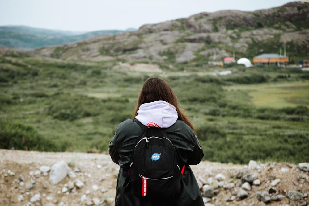 a woman with a backpack looking out over a valley