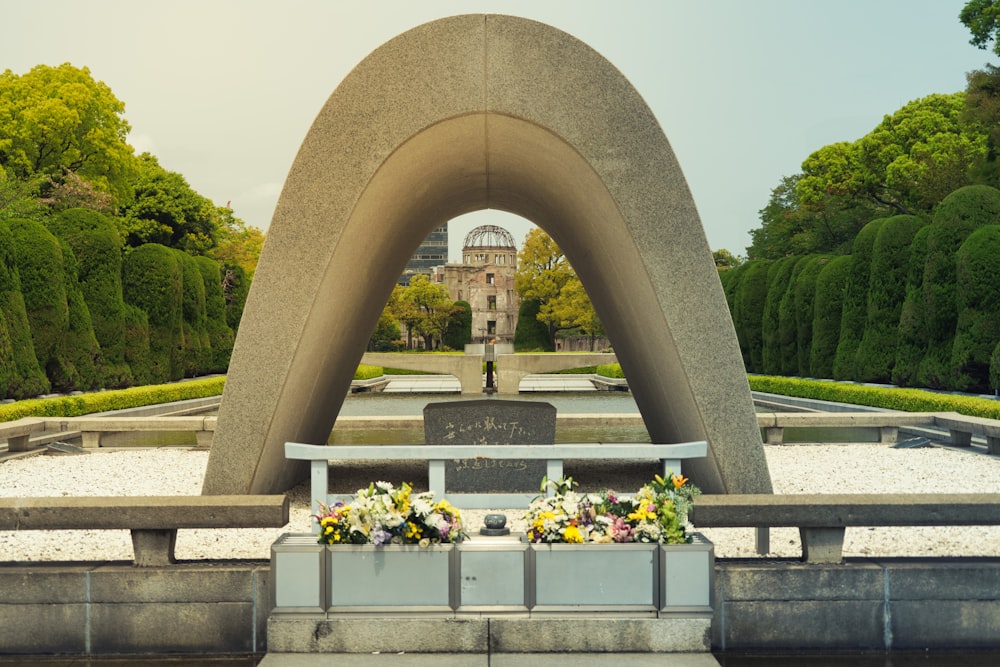 a memorial with flowers and a bench in front of it