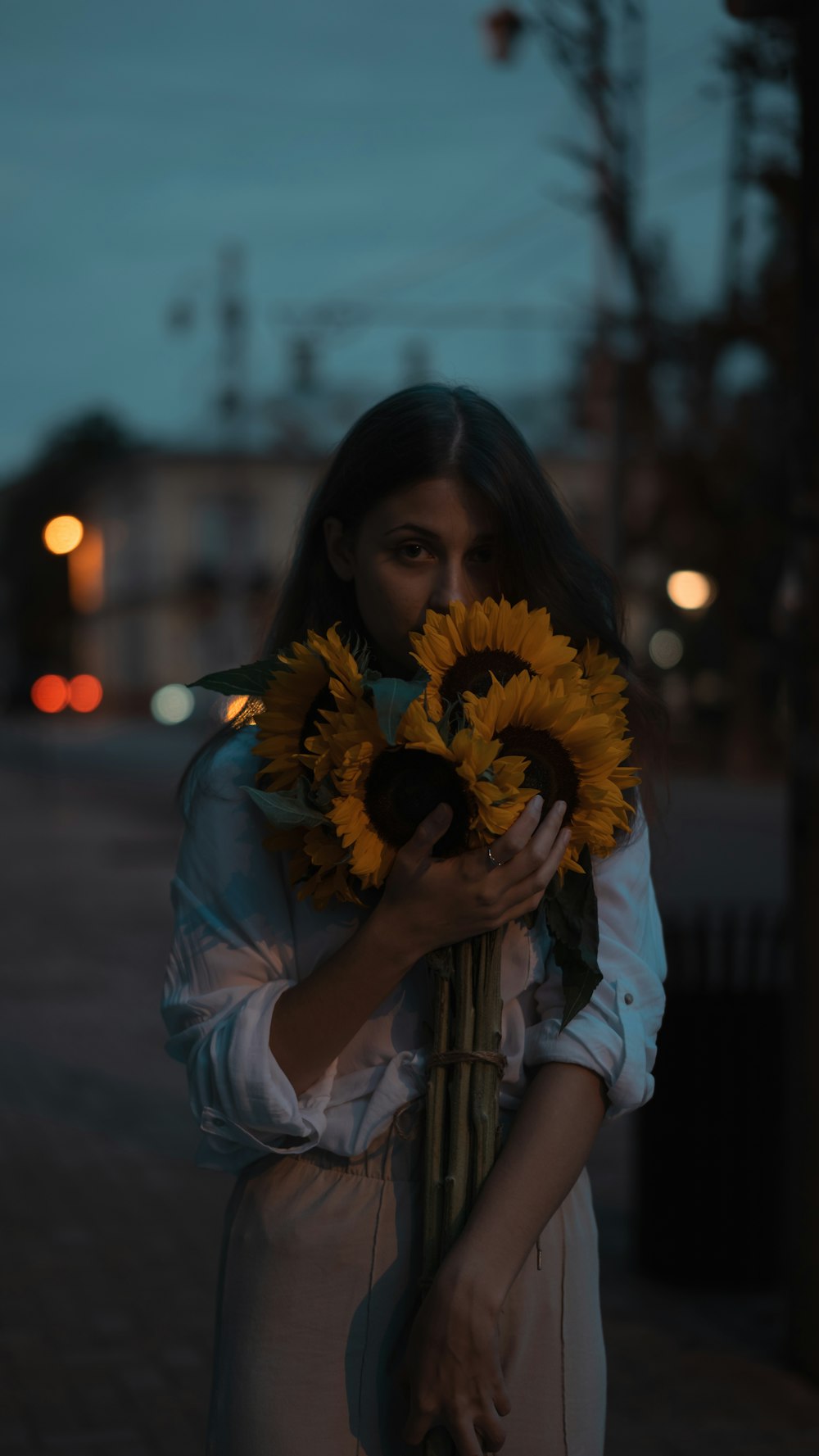 a woman holding a bunch of sunflowers in her hands