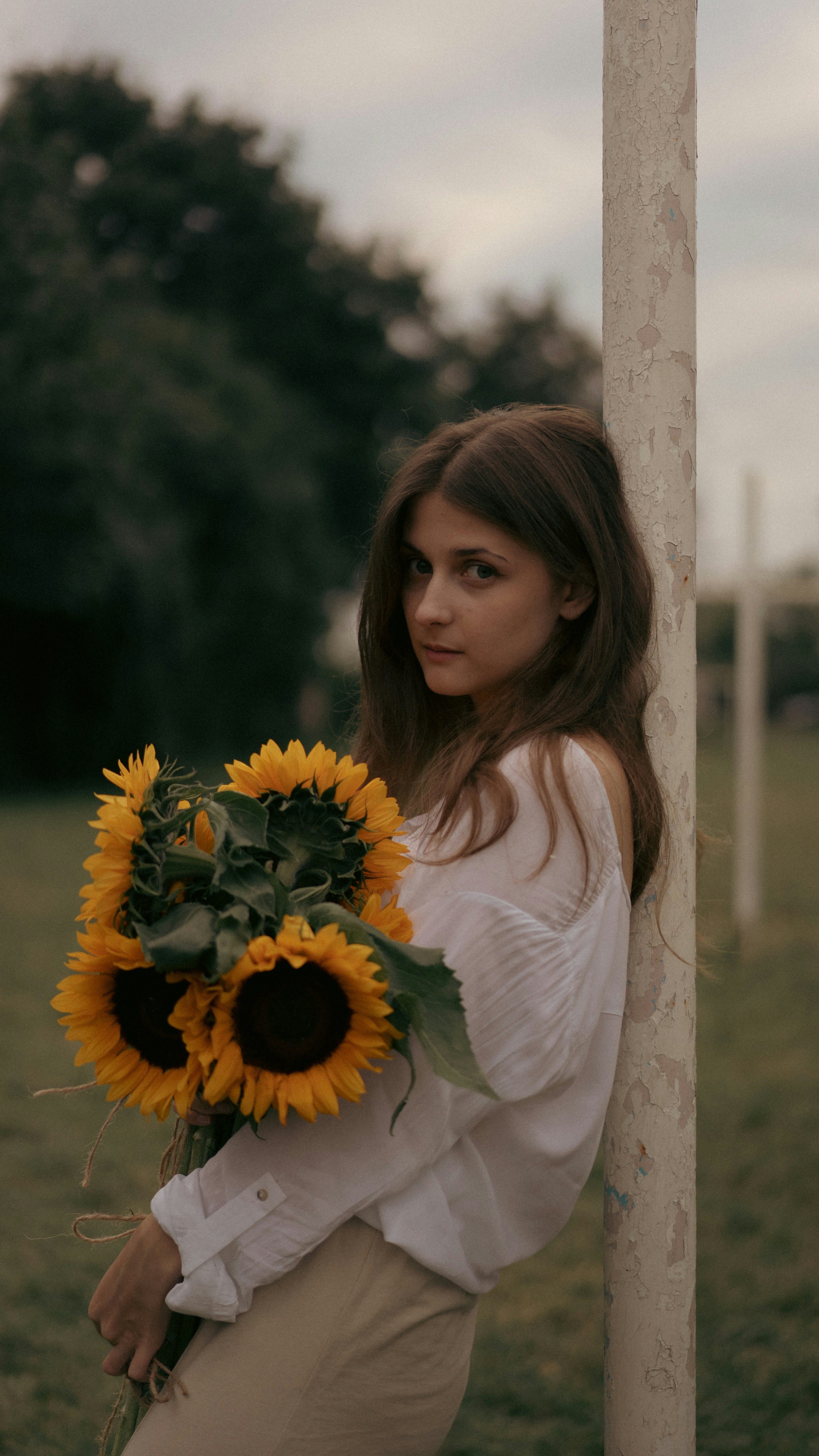 a woman holding a bouquet of sunflowers in a field