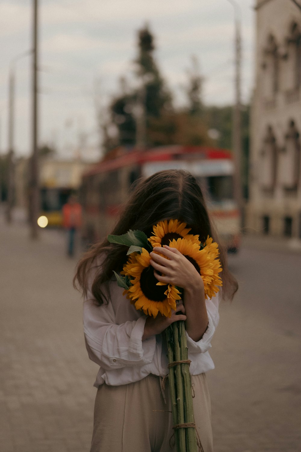 a woman holding a bouquet of sunflowers in her hands