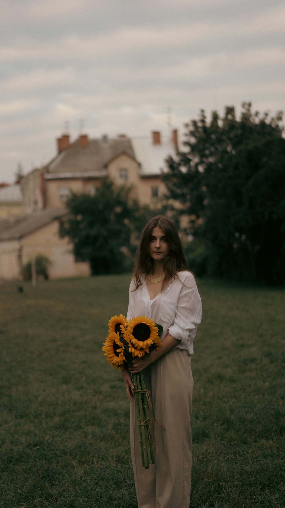 a woman standing in a field holding a bouquet of sunflowers