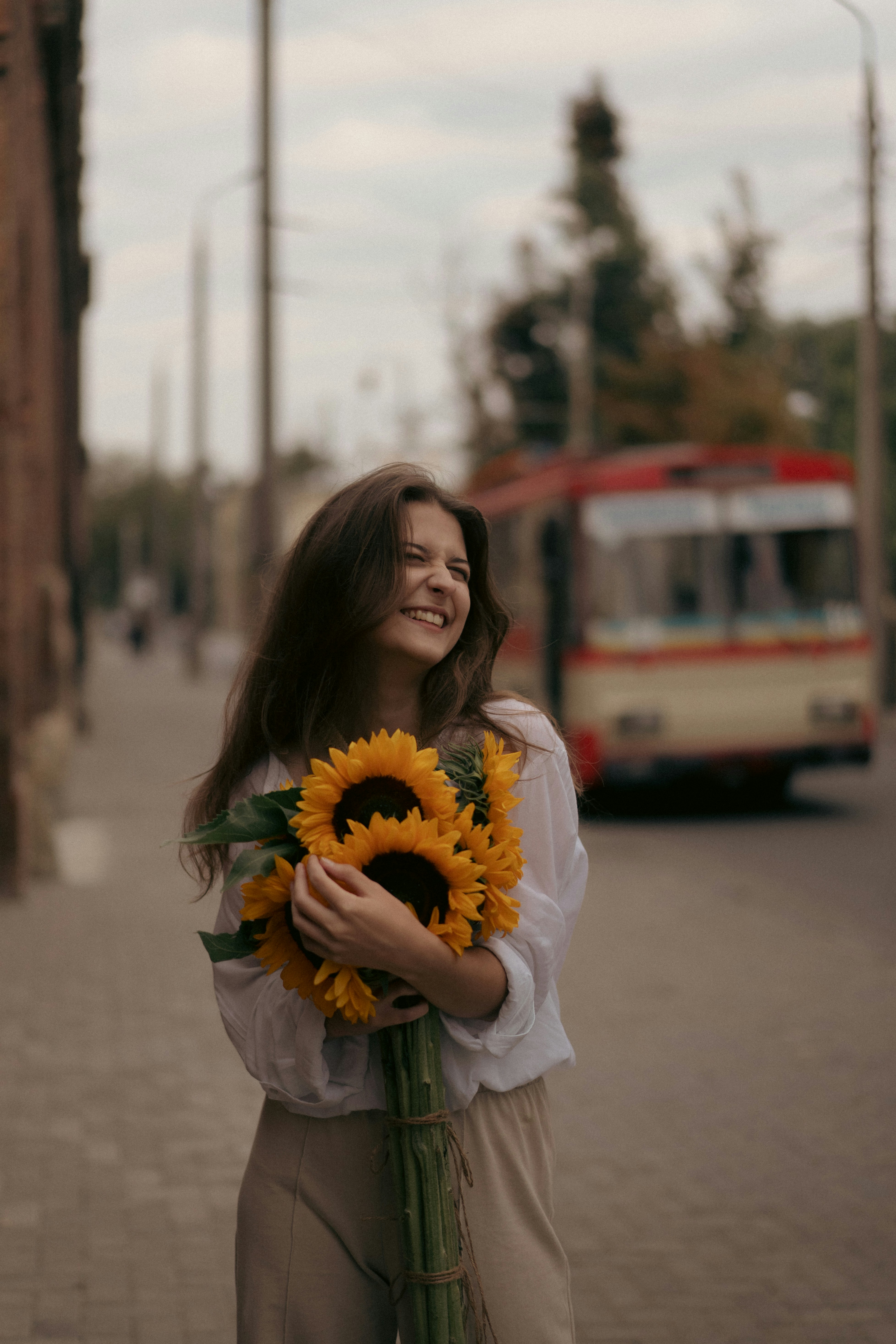 A woman holding a bouquet of sunflowers on a city street photo – Free ...
