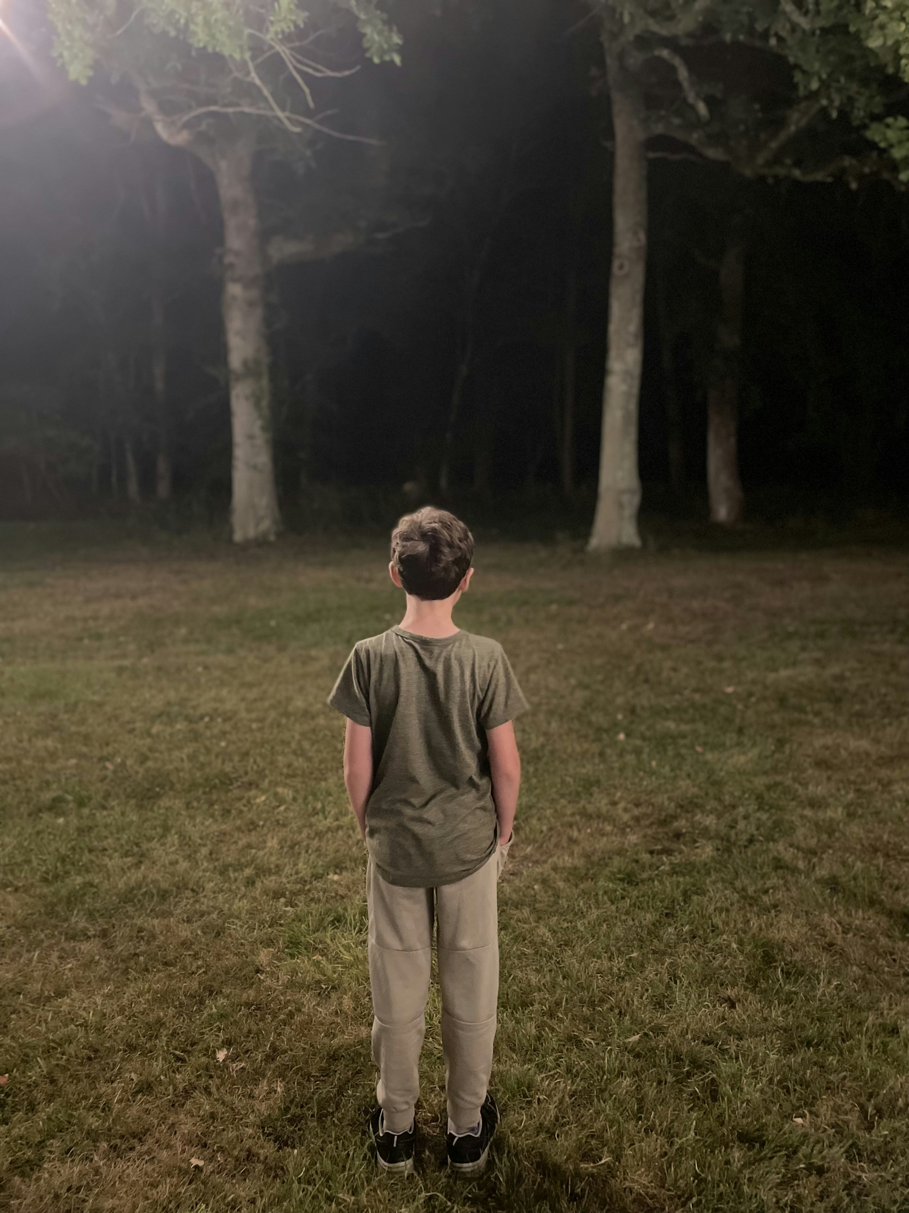 a young boy standing in the middle of a field