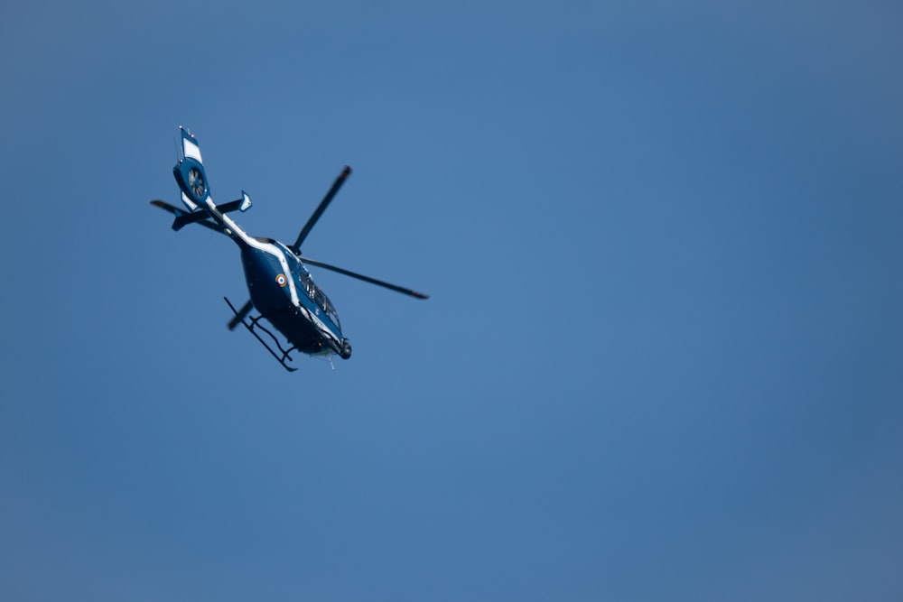 a helicopter flying through a blue sky on a sunny day