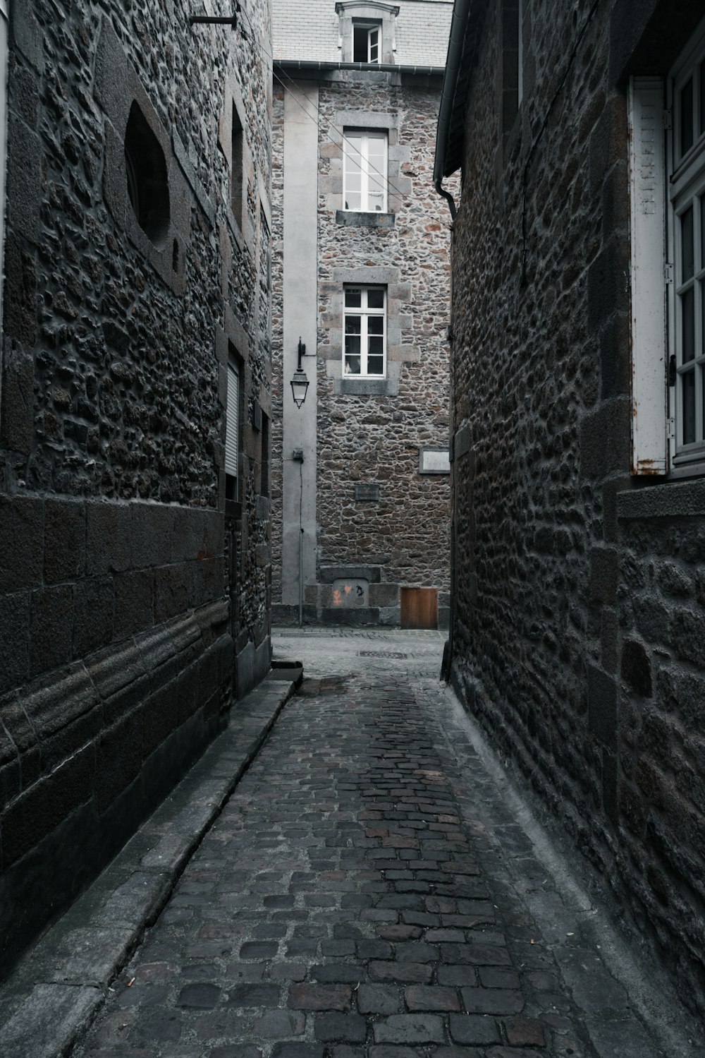 eine schmale Gasse mit einem Steingebäude im Hintergrund