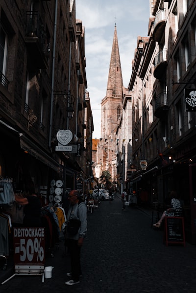 a narrow city street with a church steeple in the background