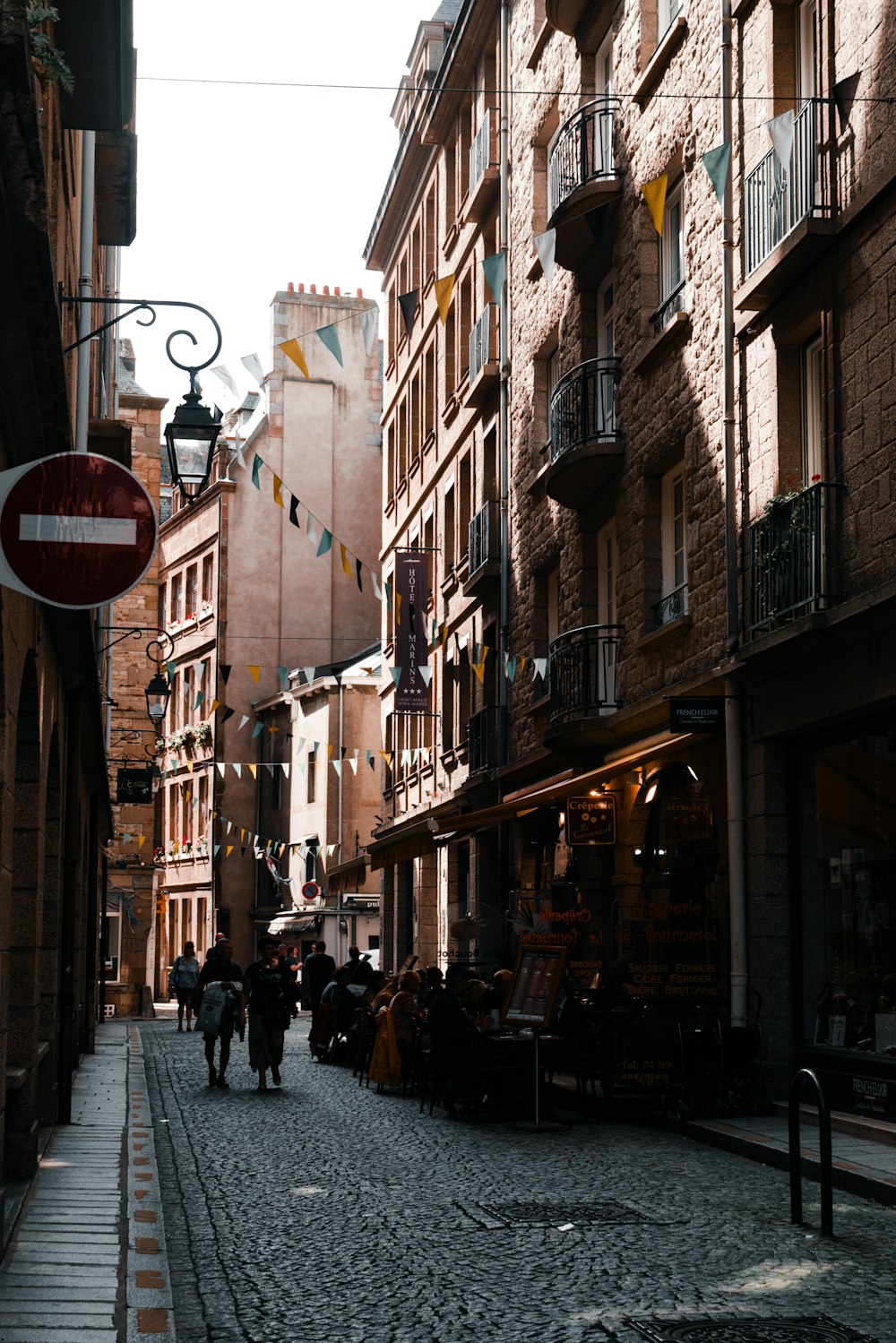 a cobblestone street with people walking down it