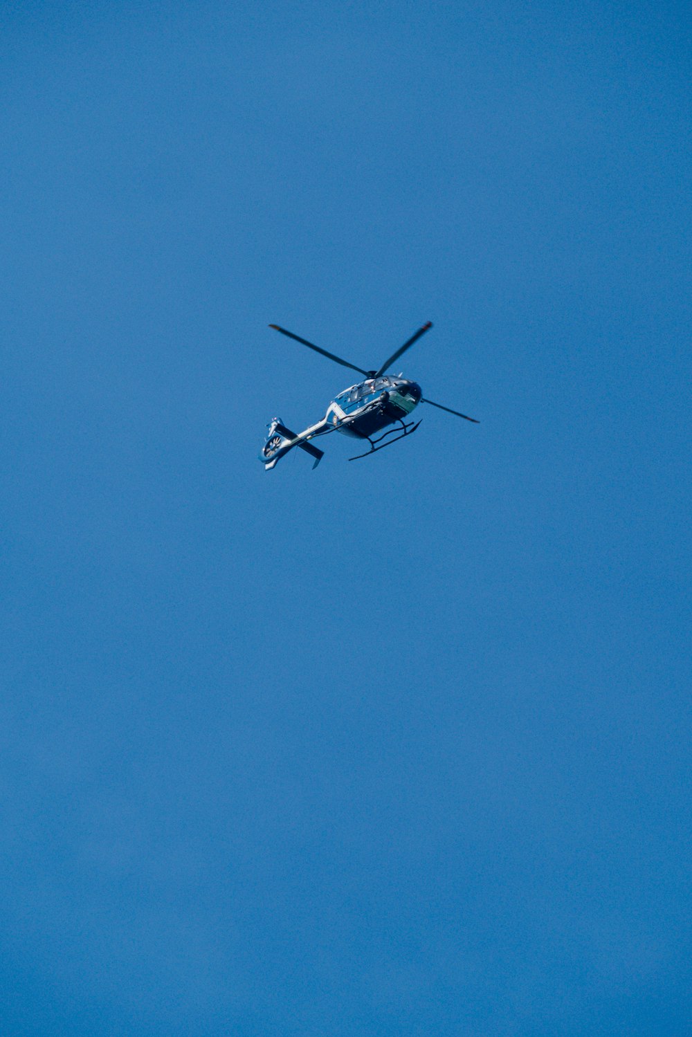 a helicopter flying through a blue sky on a sunny day