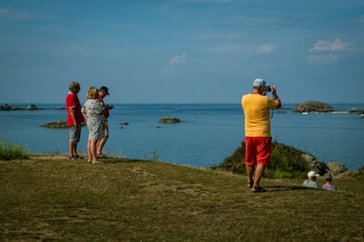 a group of people standing on top of a grass covered hillside