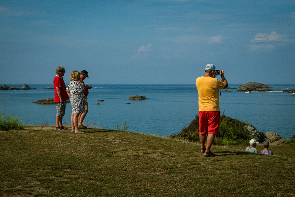 a group of people standing on top of a grass covered hillside