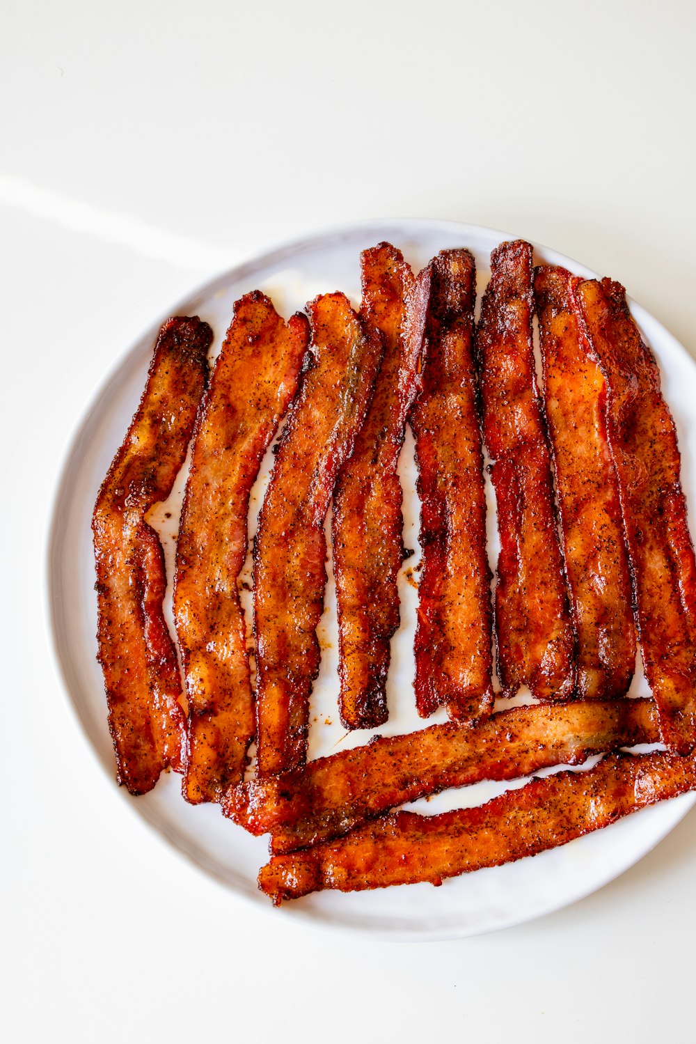 a white plate topped with bacon strips on top of a table