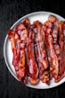 a white plate topped with bacon strips on top of a table