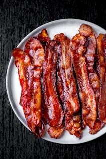 a white plate topped with bacon strips on top of a table