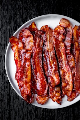 a white plate topped with bacon strips on top of a table