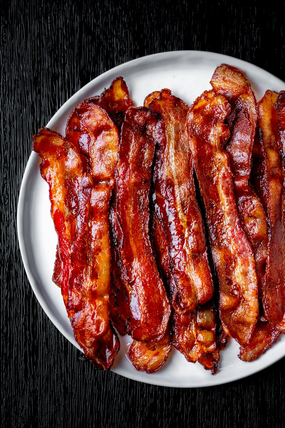 a white plate topped with bacon strips on top of a table