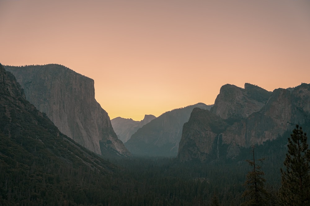 the sun is setting over the mountains in the valley